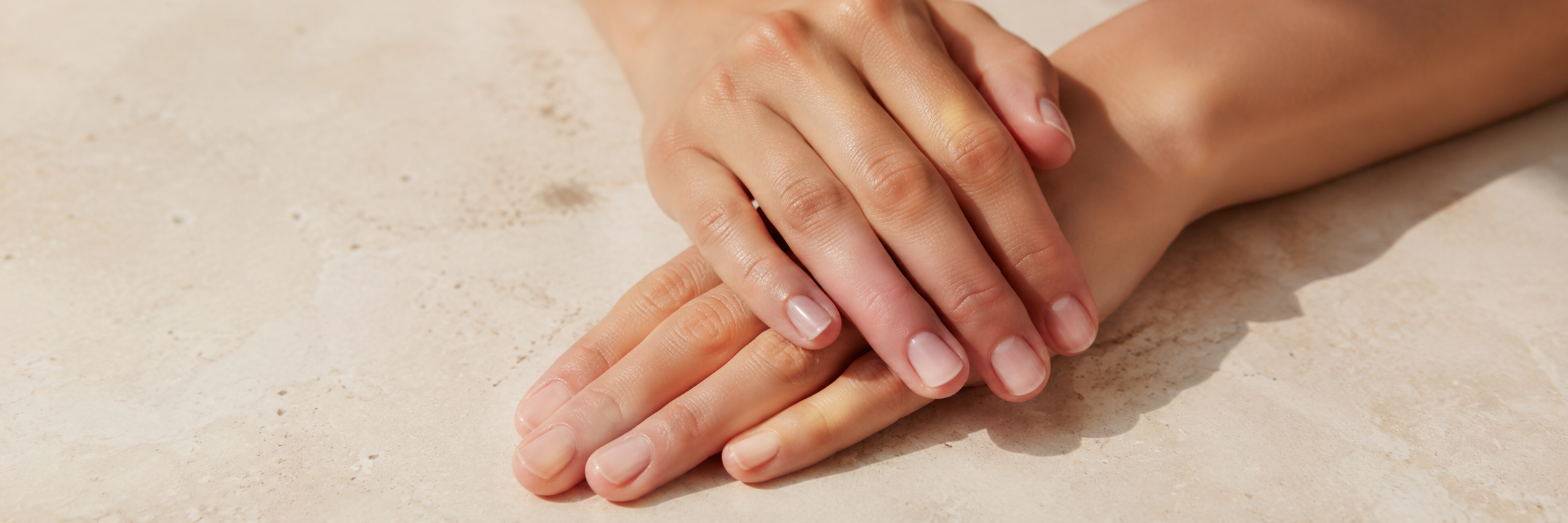 Gepflegte Hände auf Marmoroberfläche. Handpflege für stark beanspruchte Hände